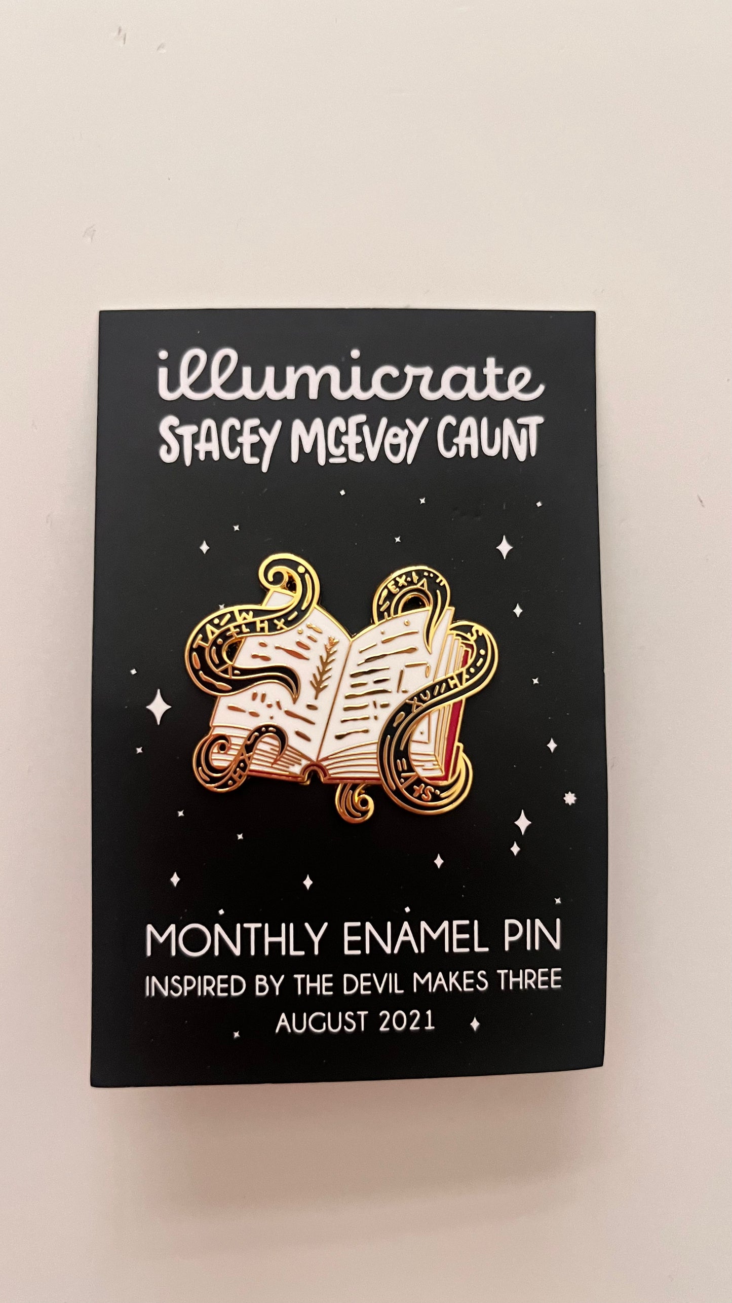 Enamel pin packaging with 'illumicrate' branding and design details.
