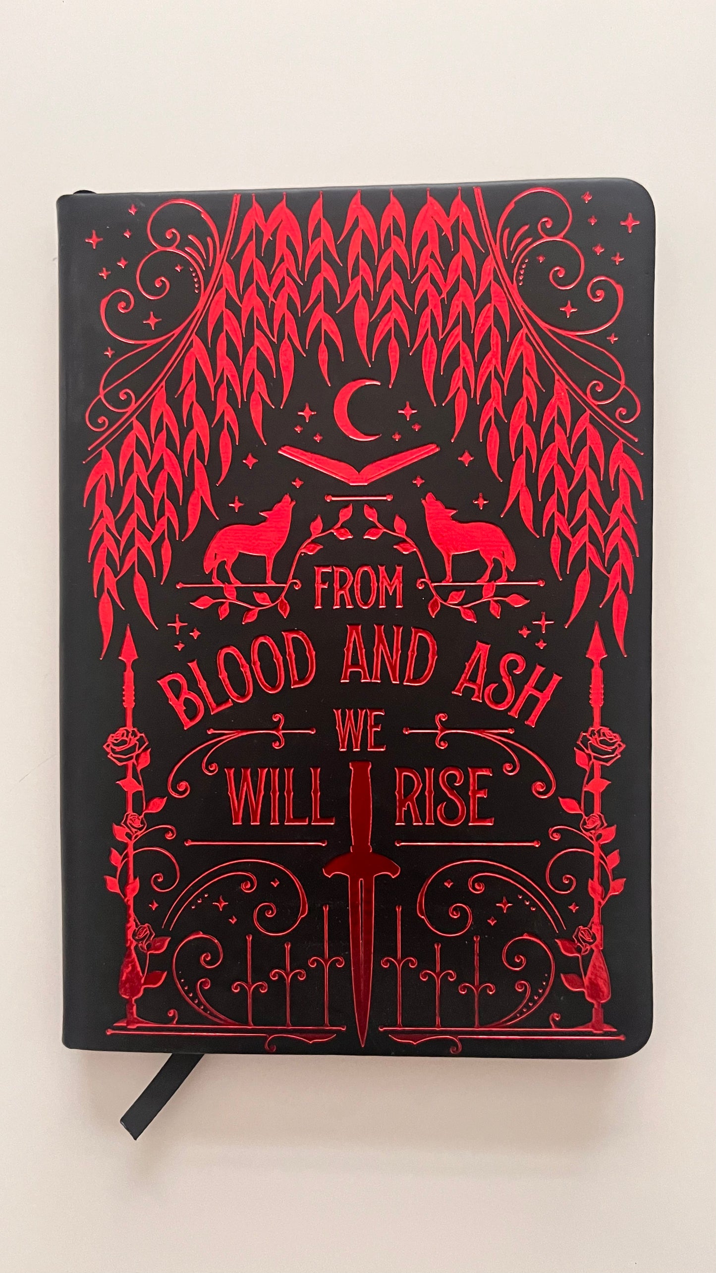 Black notebook with red decorative design and text on a white background