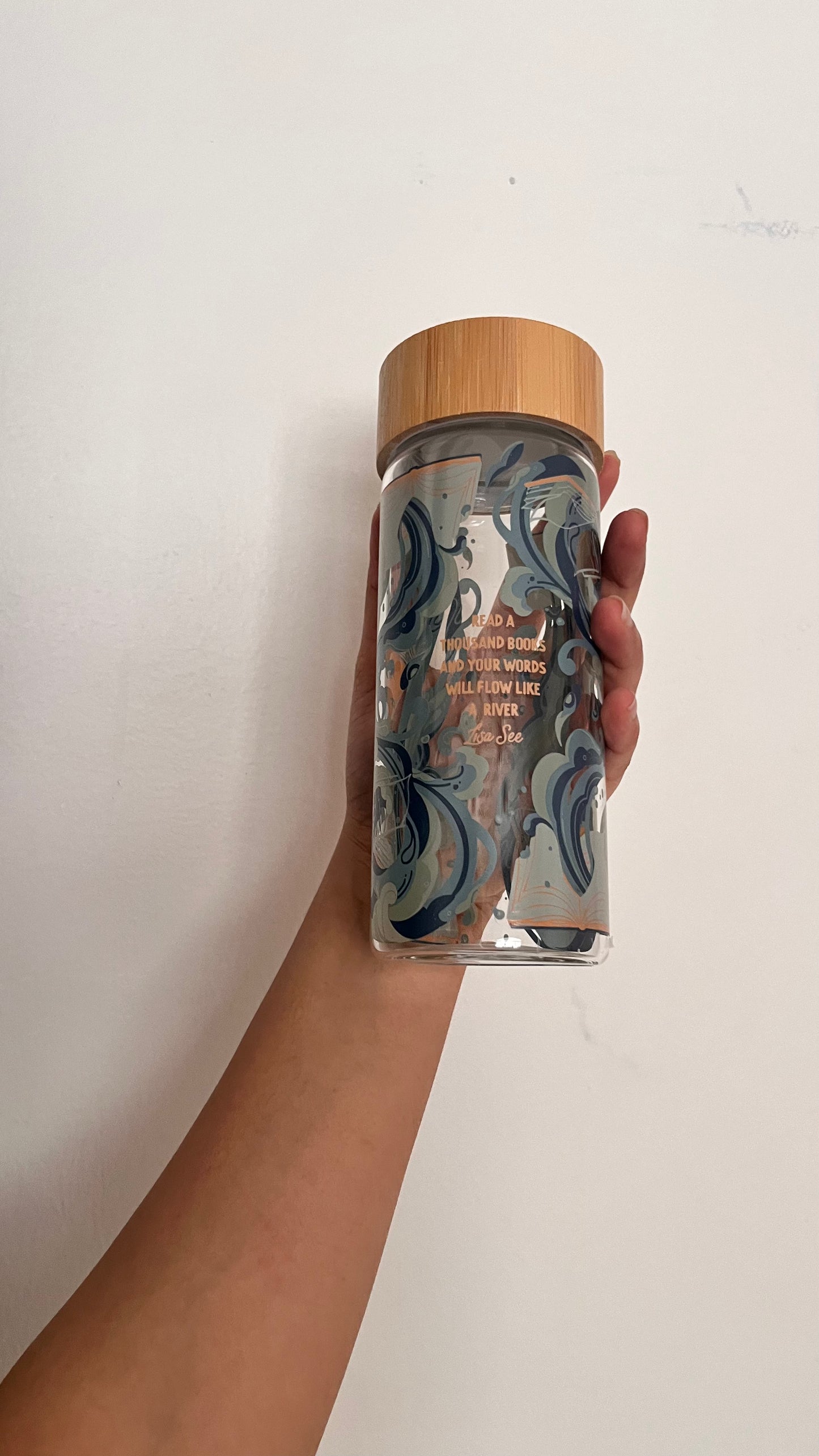 Hand holding a clear container with a wooden lid against a white background
