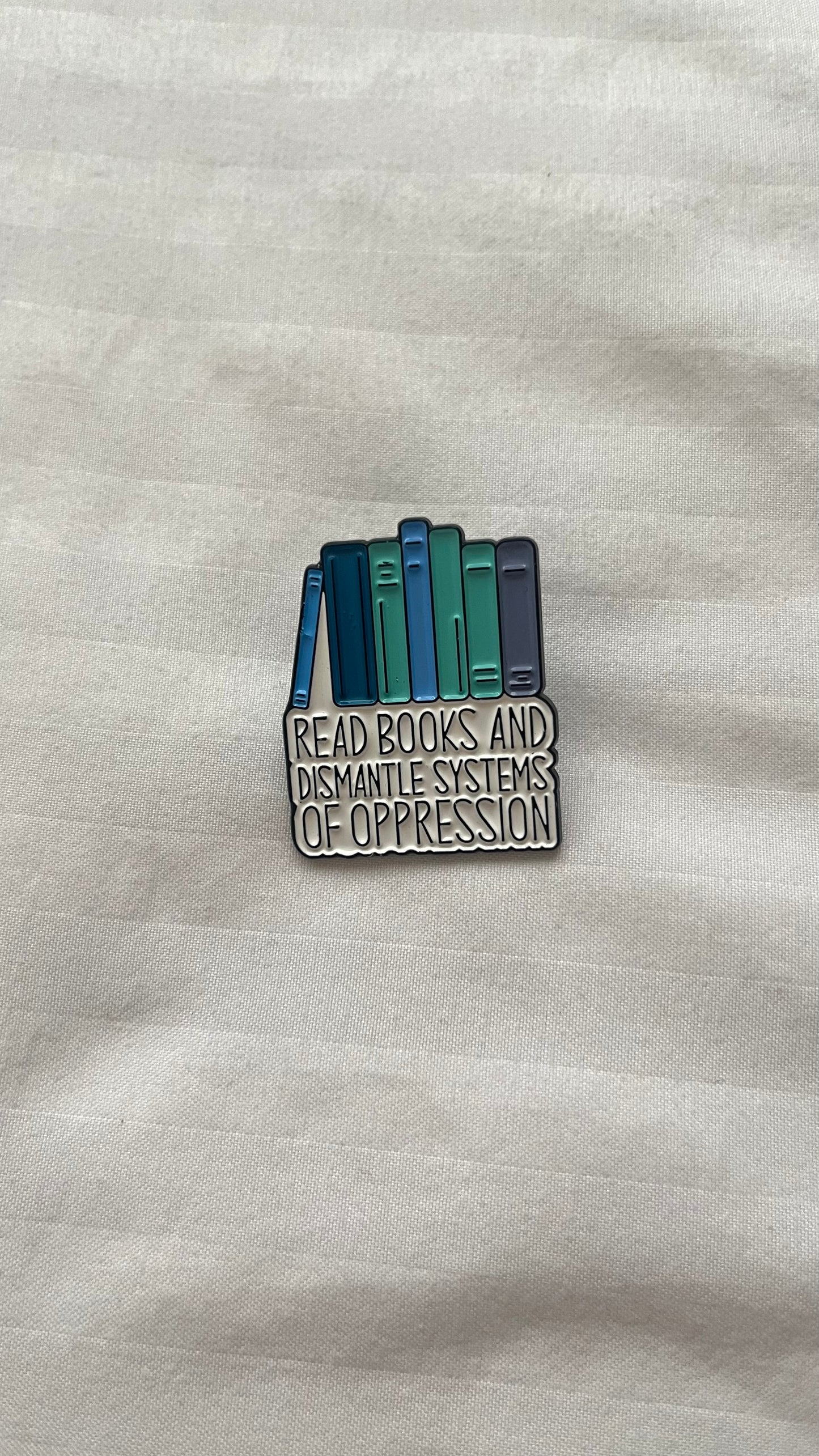 Enamel pin with quote: "Read books and dismantle the systems of oppression"