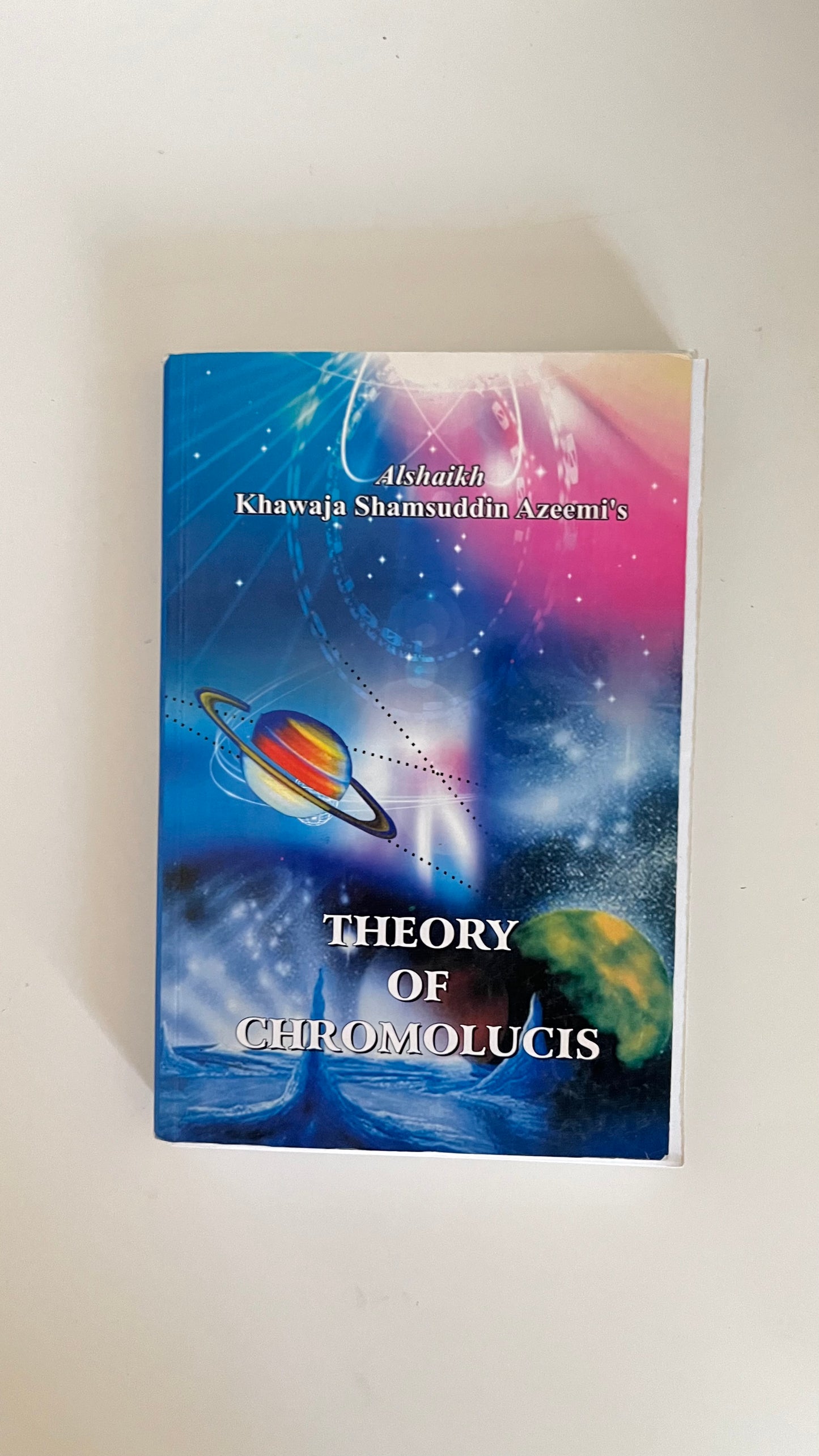 Paperback edition of Theory of Chromolucis by Khawaja Shamsuddin Azeemi with abstract visuals depicting the flow of energy and consciousness.