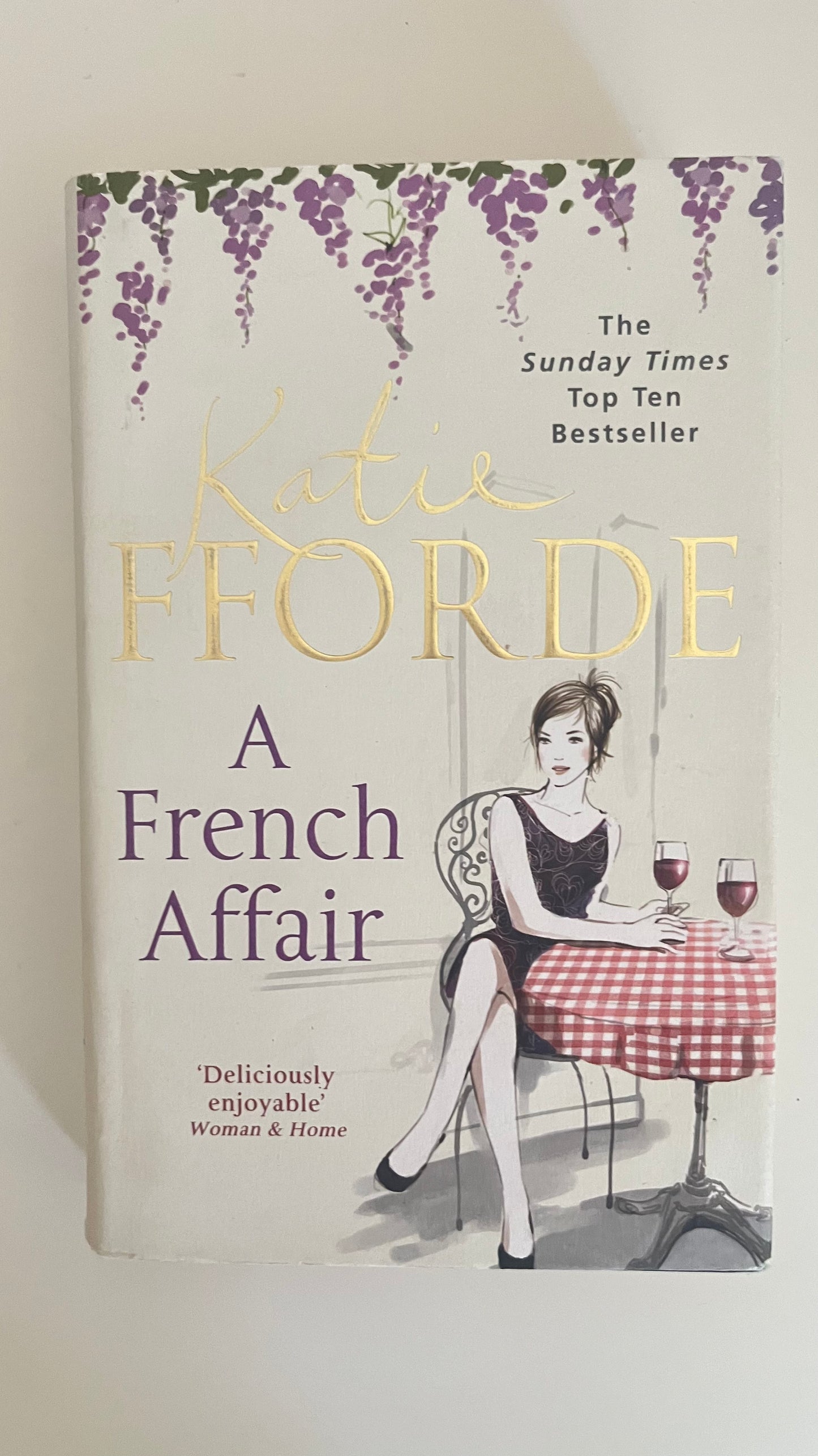 Paperback edition of A French Affair by Katie Fforde with a charming illustrated cover of Parisian cafes and antiques.

