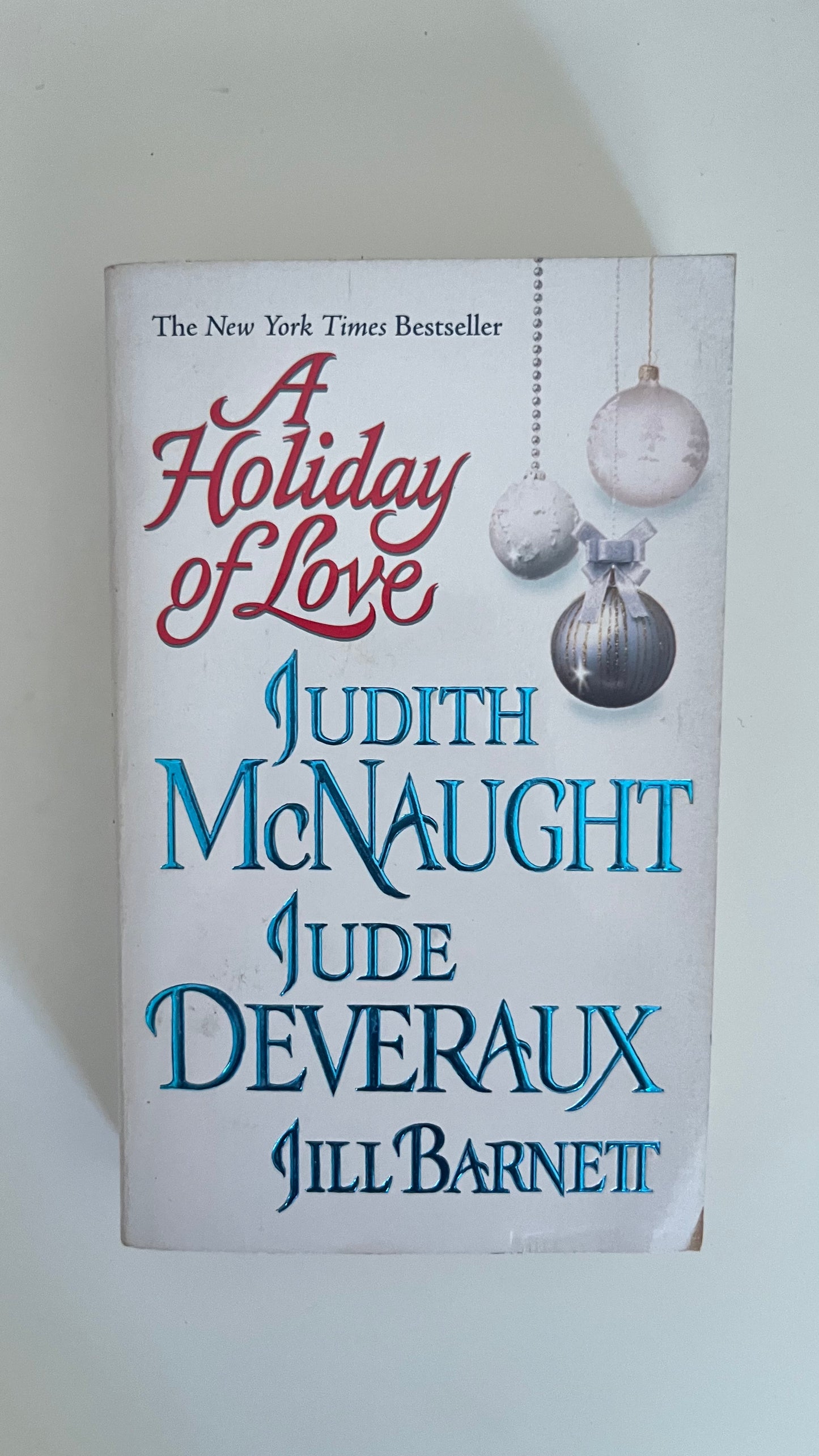 Paperback of A Holiday of Love with a cozy, wintry cover featuring snowflakes and hearts.

