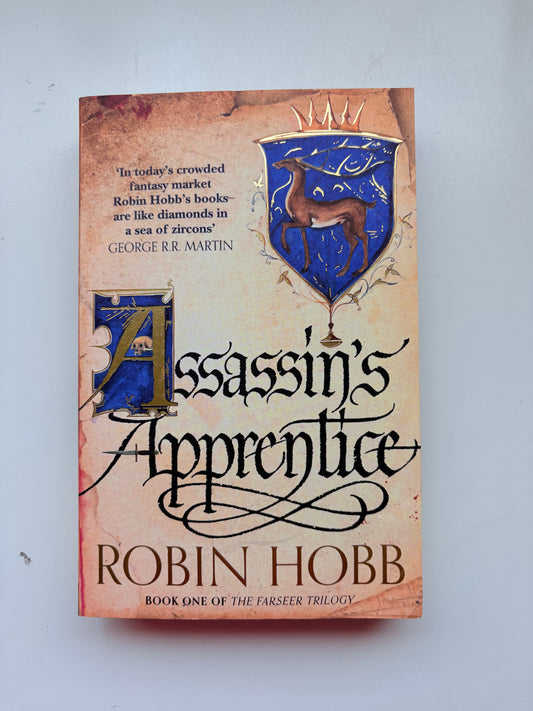 Book titled 'Assassin's Apprentice' by Robin Hobb on a light gray background
