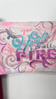 Decorative pillow with 'The Heart is All Fire' text and colorful design on a white background