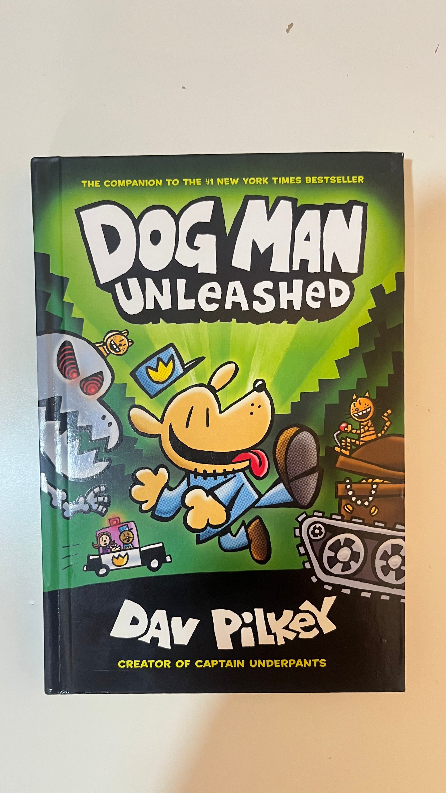 Hardback edition of Dog Man: Unleashed by Dav Pilkey featuring a colorful cartoon-style cover with Dog Man in a heroic pose.


