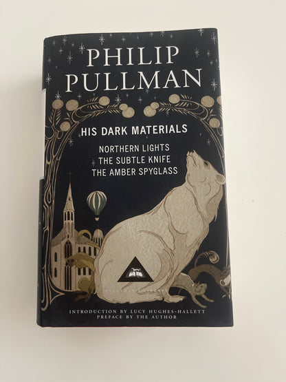 Book titled 'His Dark Materials' by Philip Pullman on a white background
