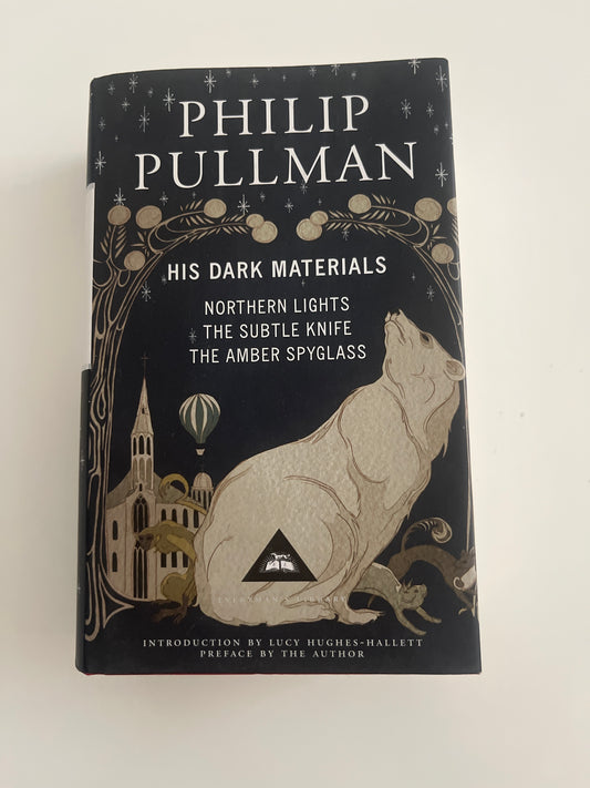 Book titled 'His Dark Materials' by Philip Pullman on a white background