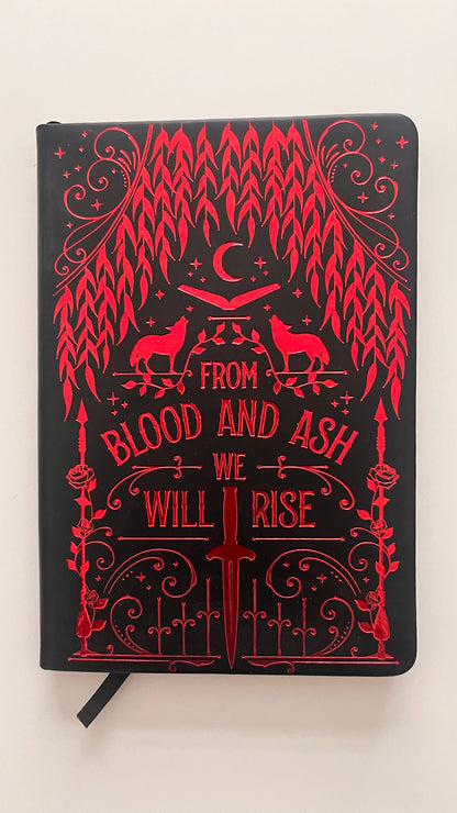 Black notebook with red decorative design and text on a white background