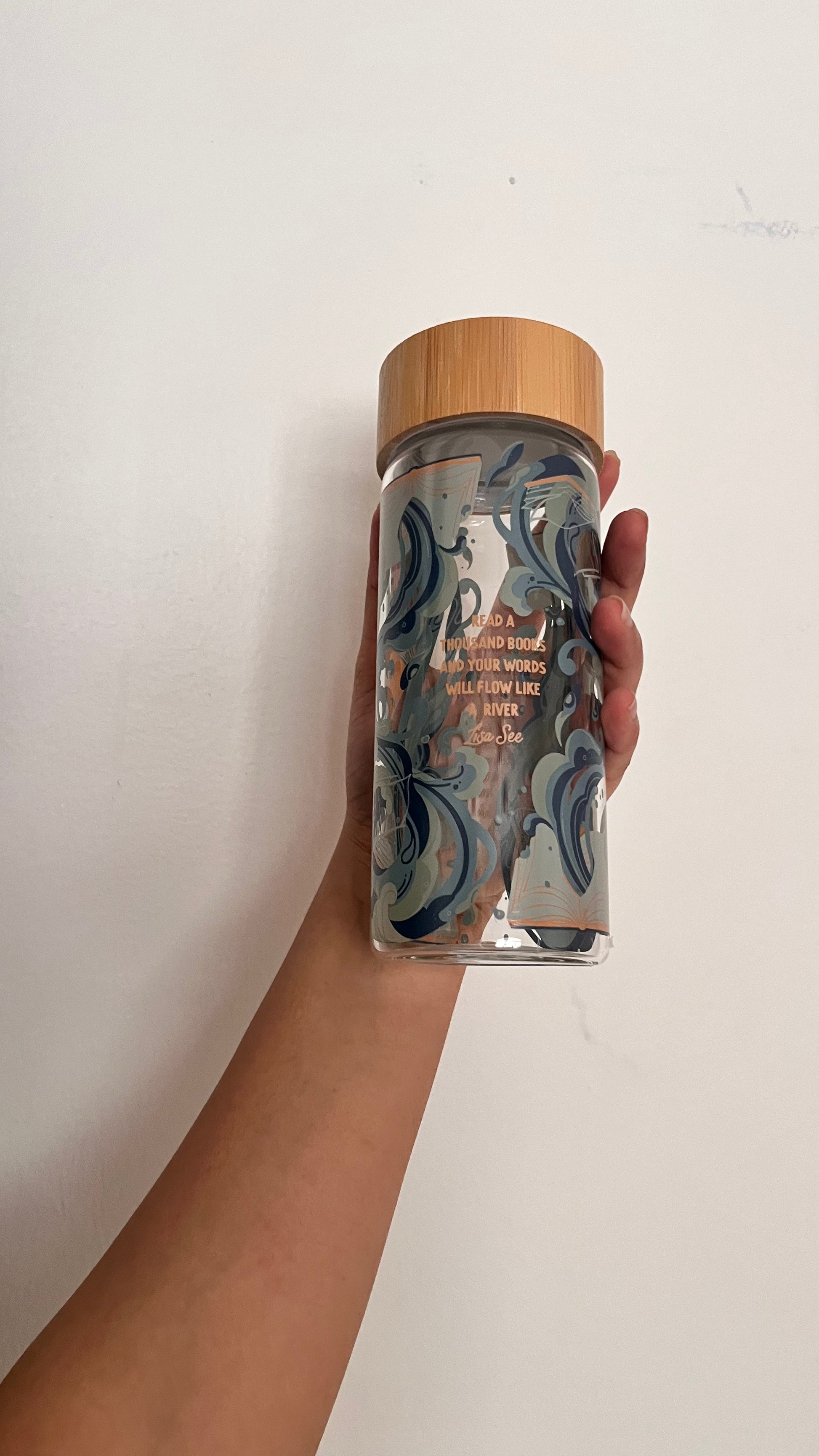 Hand holding a clear container with a wooden lid against a white background