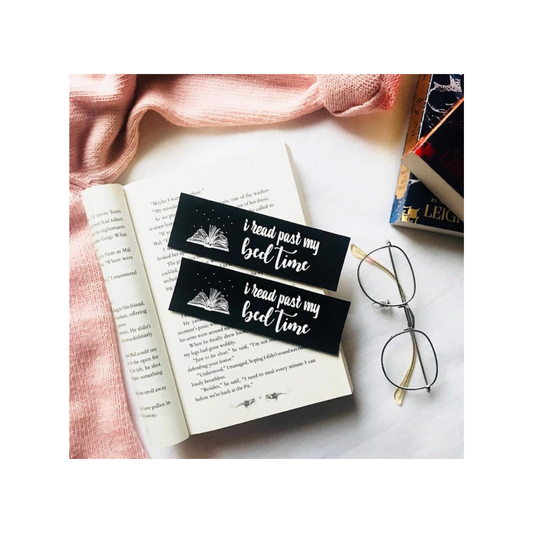 Bookmarks with text on an open book next to glasses and a pink fabric