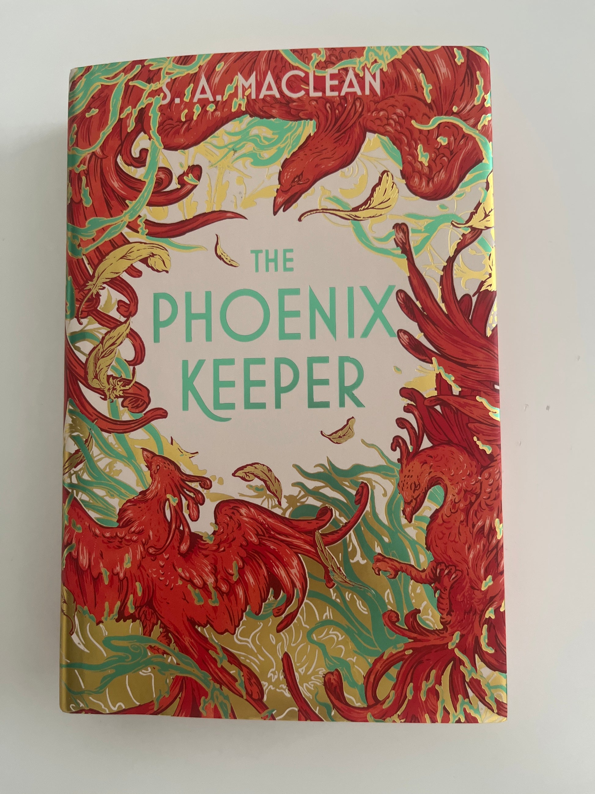 Book cover of 'The Phoenix Keeper' with red phoenix illustrations on a beige background