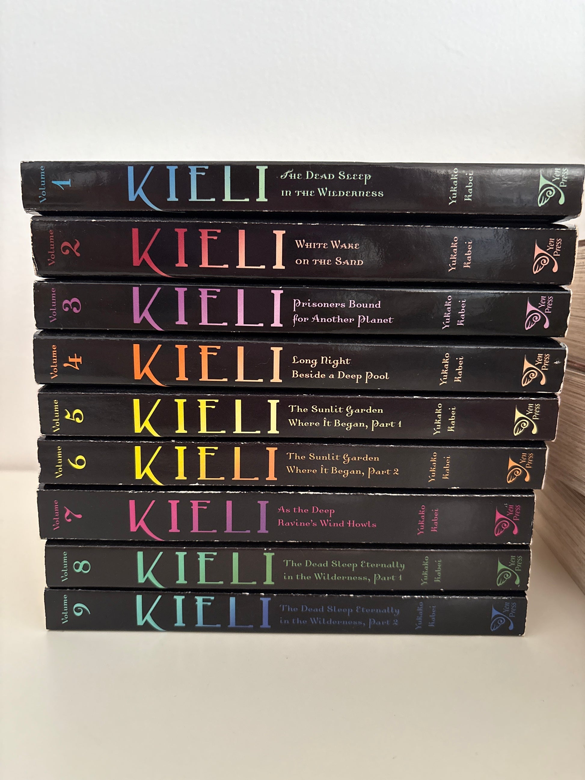 Row of black books titled 'Kiei I' with colorful lettering on a white background