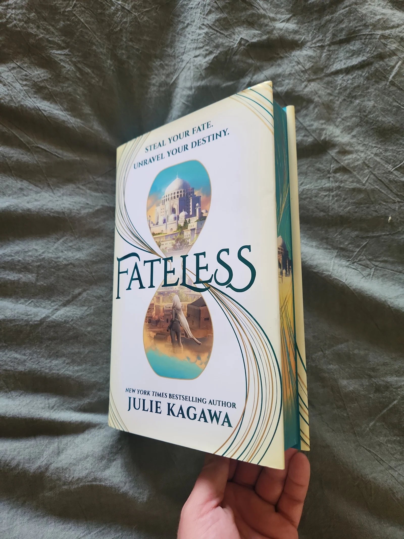 Book titled 'Fateless' by Julie Kagawa held against a dark fabric background