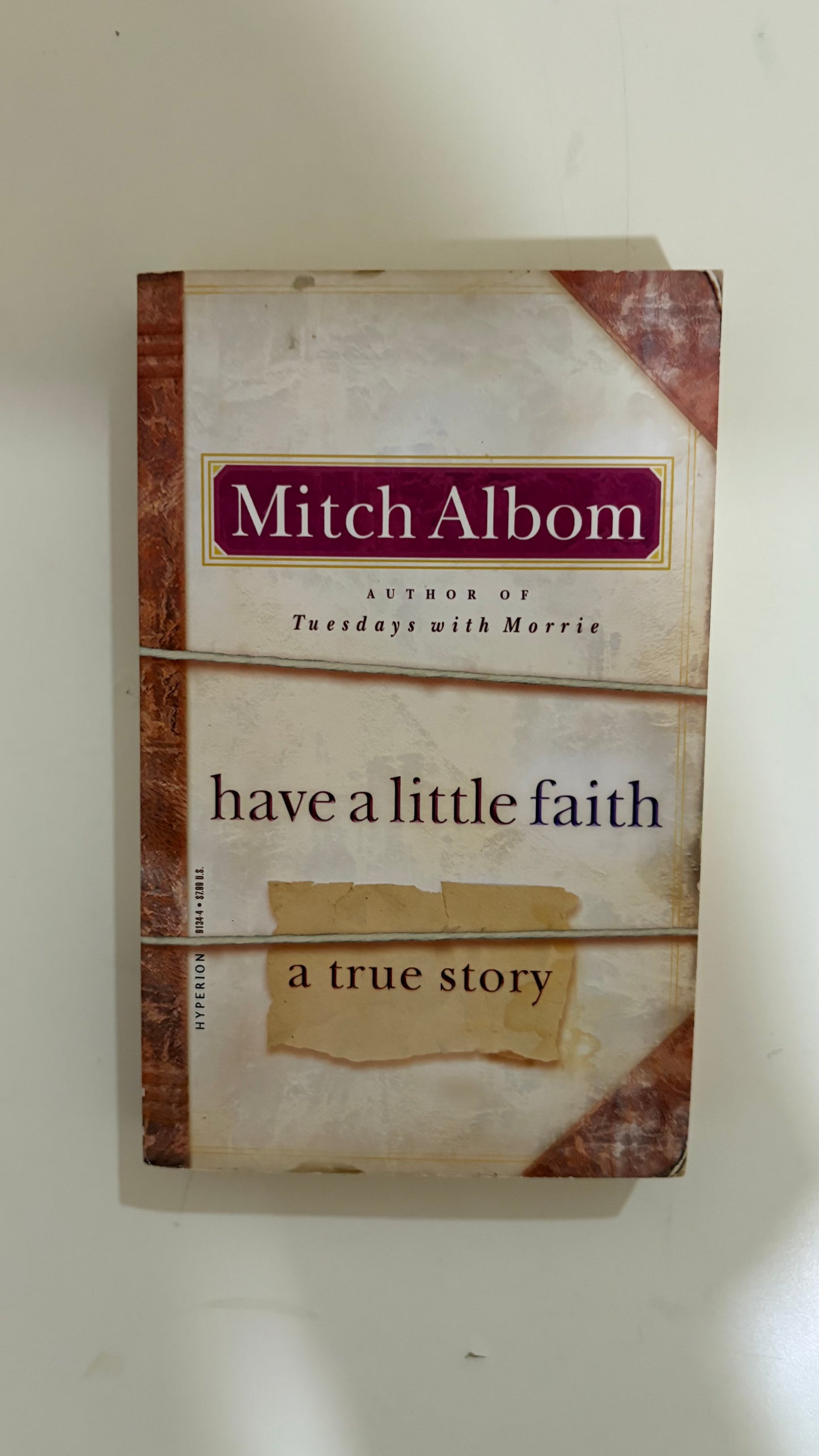A paperback copy of Mitch Albom's book 'have a little faith: a true story' resting on a light-colored surface.