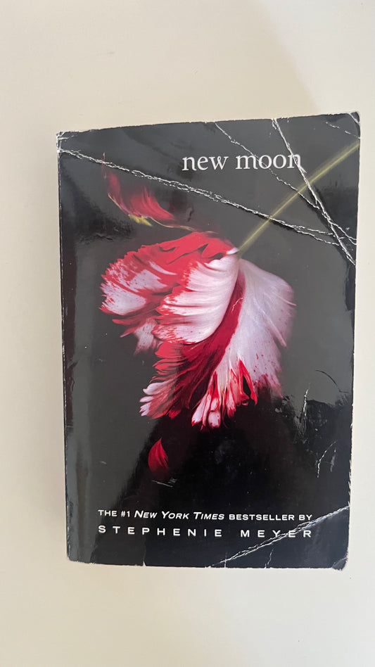Paperback edition of New Moon by Stephenie Meyer with the iconic white flower cover symbolizing Bella's heartbreak.

