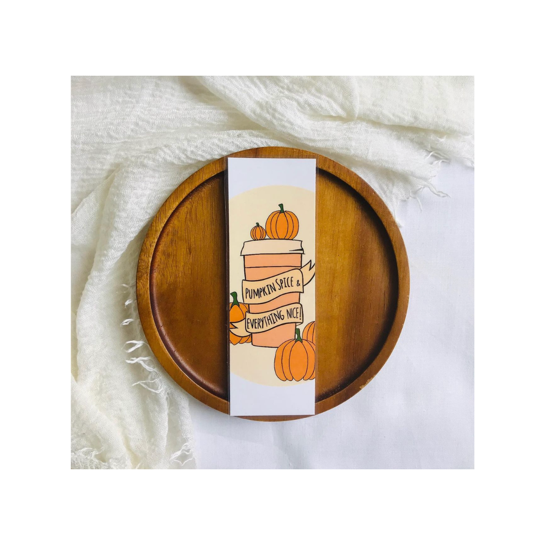 Wooden plate with a decorative card featuring pumpkins and text on a white fabric background