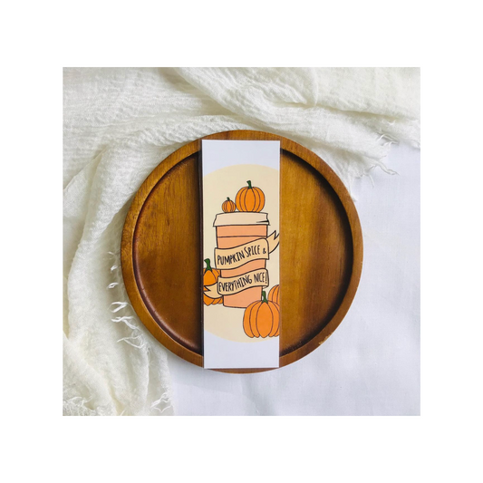 Wooden plate with a decorative card featuring pumpkins and text on a white fabric background