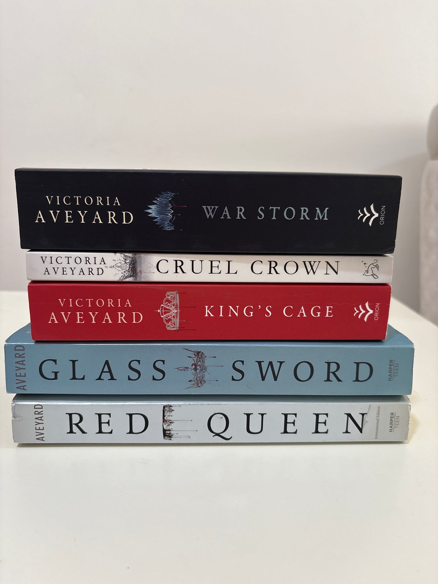 Five books by Victoria Aveyard titled 'War Storm', 'Cruel Crown', 'King's Cage', 'Glass Sword', and 'Red Queen' on a white background.