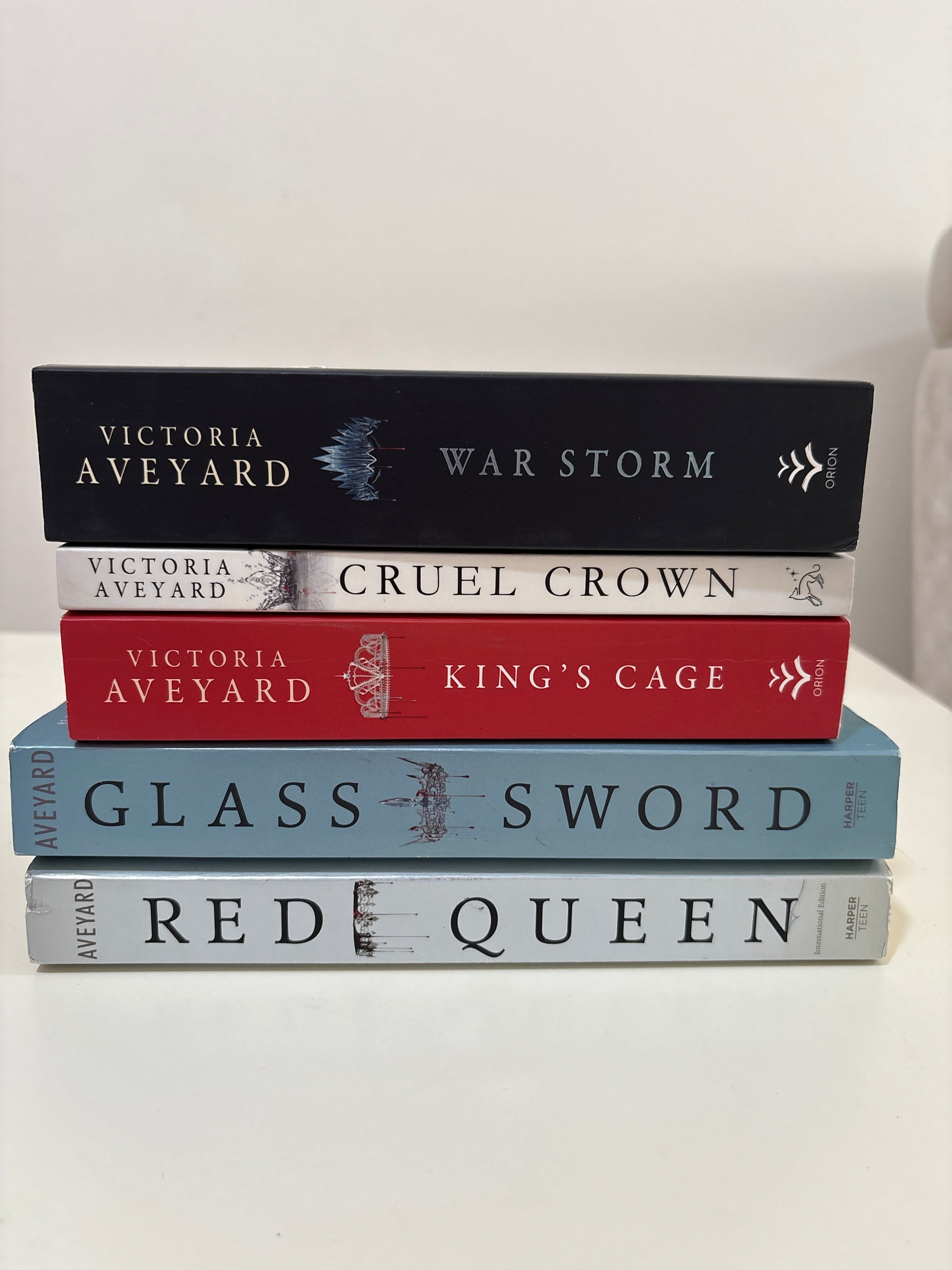 Five books by Victoria Aveyard titled 'War Storm', 'Cruel Crown', 'King's Cage', 'Glass Sword', and 'Red Queen' on a white background.