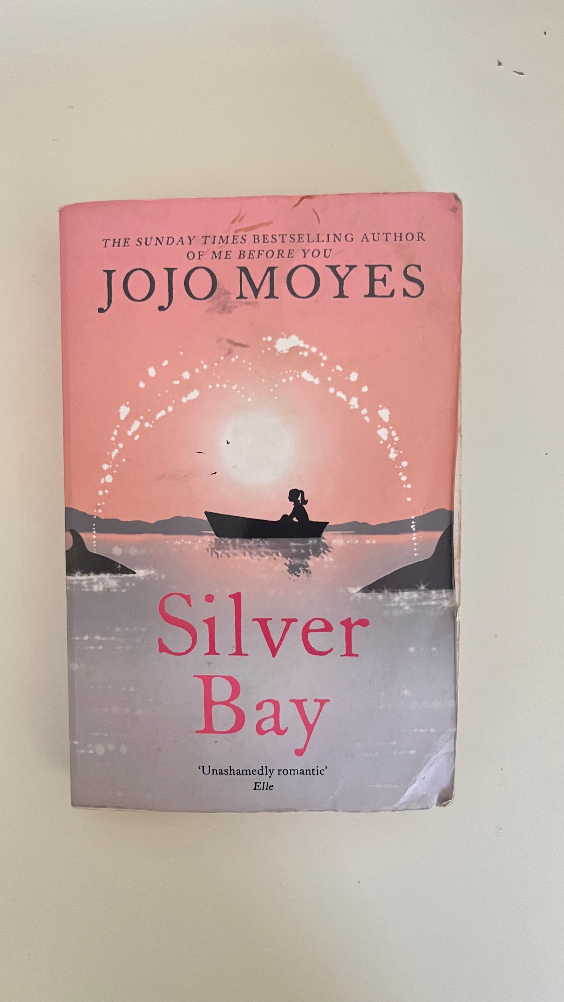 Paperback of Silver Bay by Jojo Moyes with a peaceful beach-themed cover and soft pastel tones.

