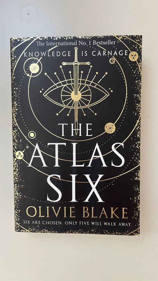 Paperback edition of The Atlas Six by Olivie Blake featuring a mysterious, alchemical design with dark academia vibes.

