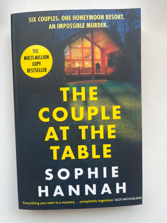 Paperback of The Couple at the Table by Sophie Hannah with a mysterious and chilling dinner party-themed cover.

