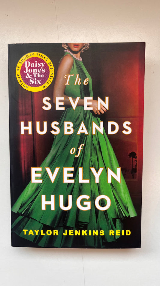 Book cover of 'The Seven Husbands of Evelyn Hugo' by Taylor Jenkins Reid with a green dress on a black background.