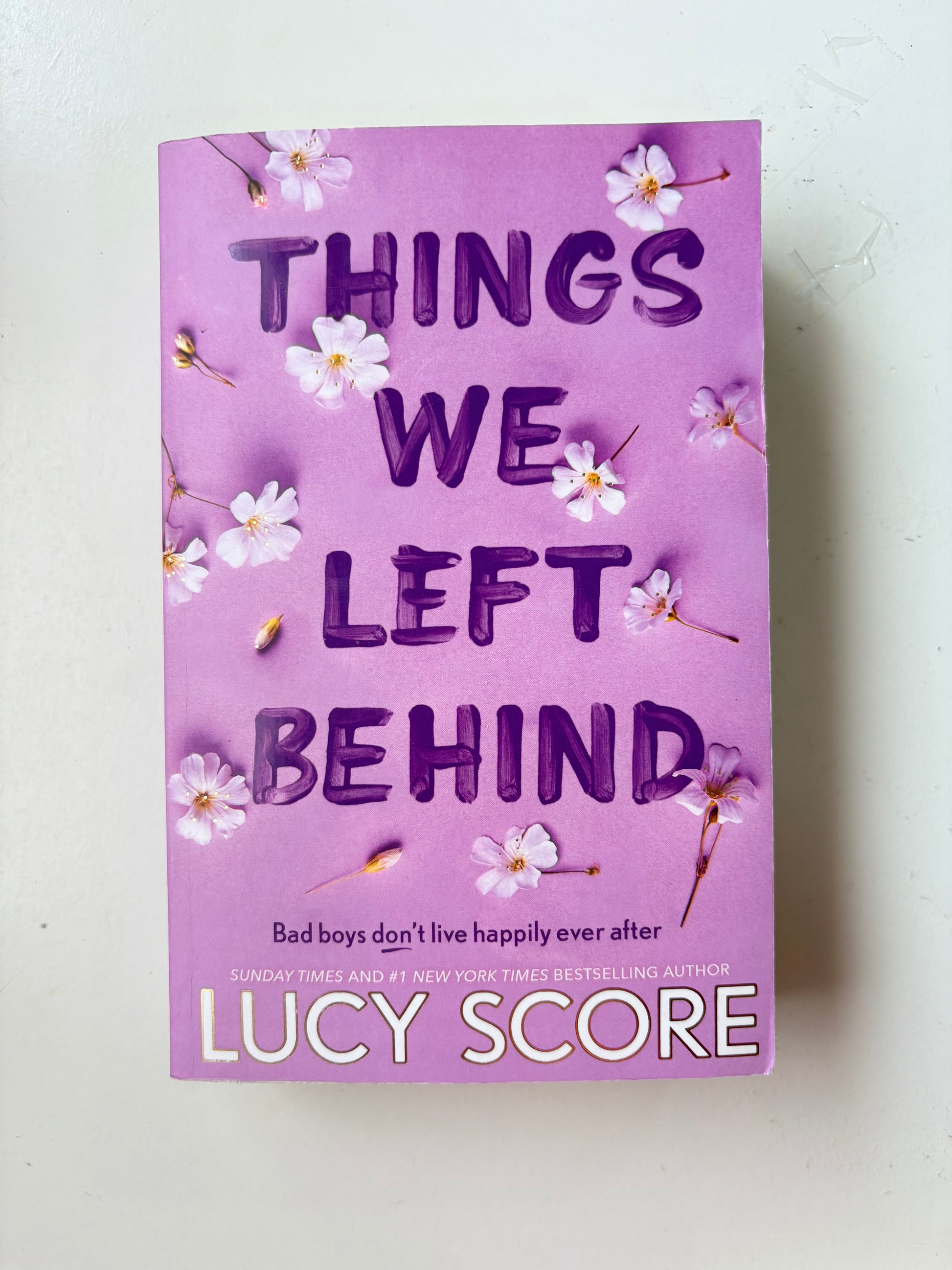 Book titled 'Things We Left Behind' by Lucy Score with decorative flowers on a light background