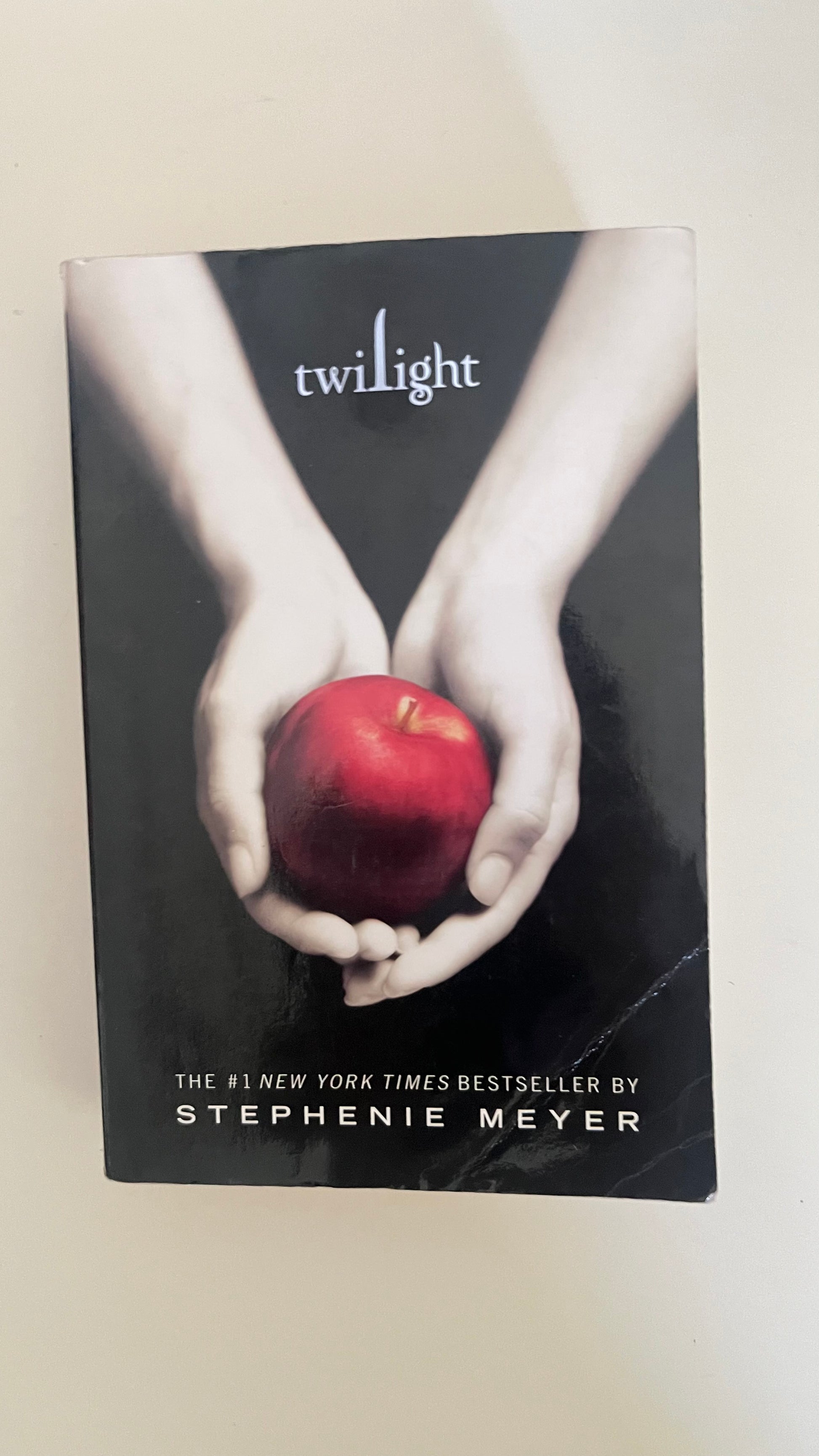 Paperback edition of Twilight by Stephenie Meyer featuring the iconic hands-holding-apple cover.


