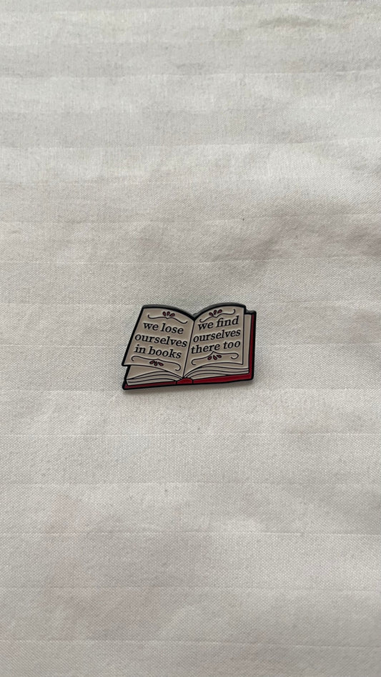 Enamel pin with quote: "We lose ourselves in books, we find ourselves there too"
