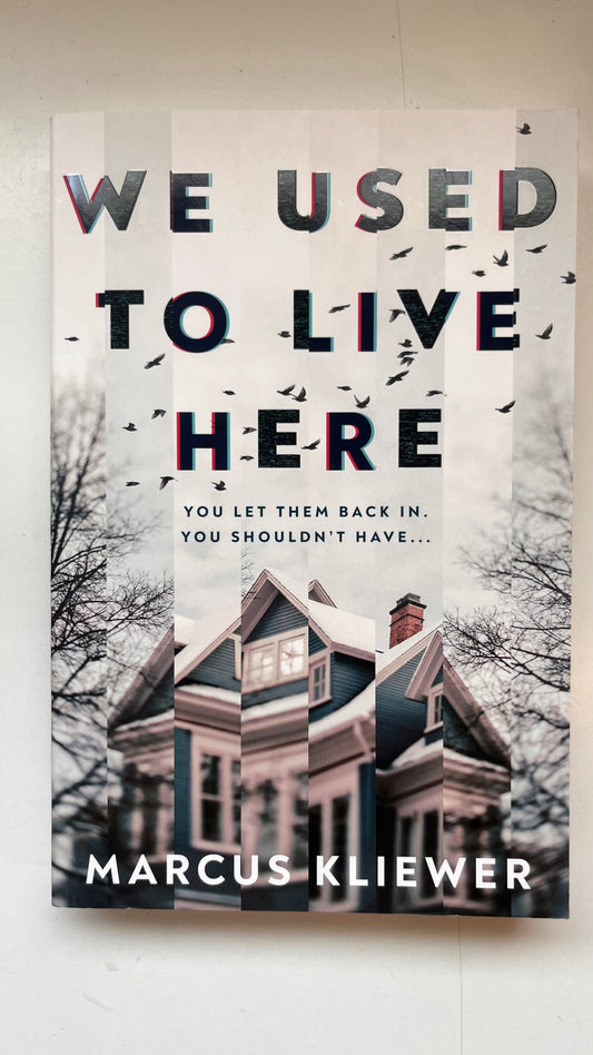 Book cover of 'We Used to Live Here' by Marcus Kliewer with a house and trees in the background.
