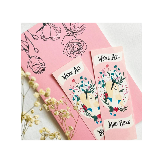 Two pink bookmarks with floral designs and text on a pink background with flowers.