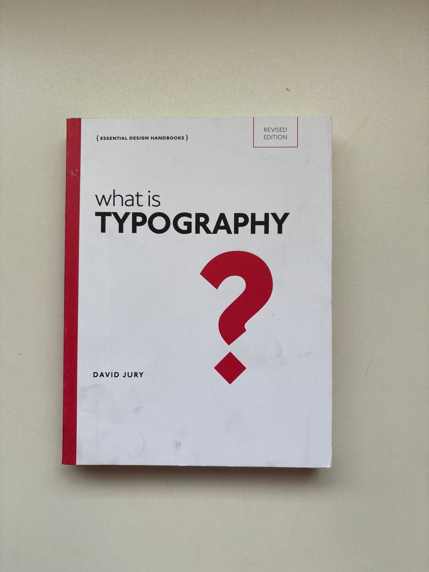 Book titled 'What is Typography?' with a red question mark on a beige background