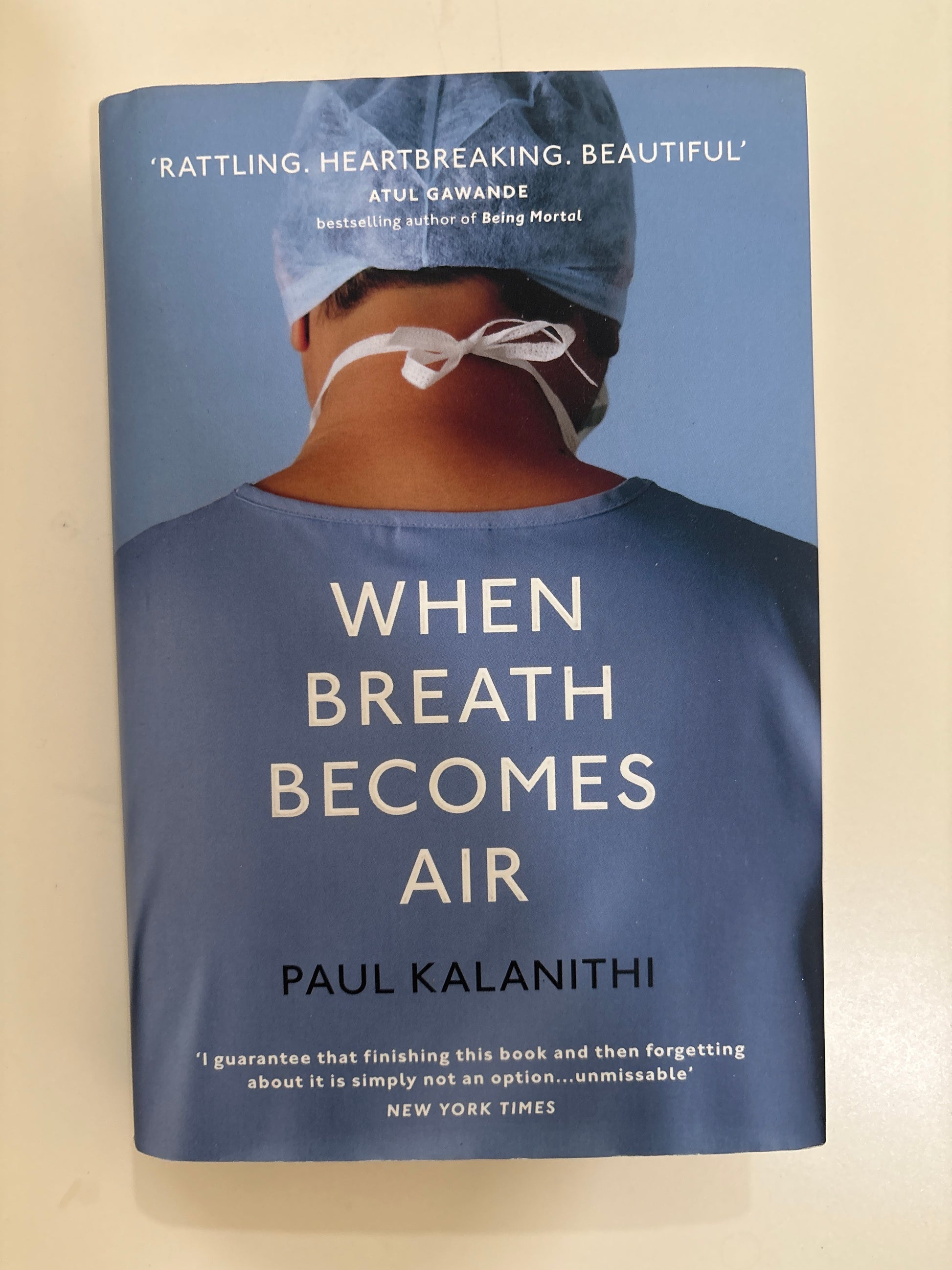 Book cover of 'When Breath Becomes Air' by Paul Kalanithi with a person in a surgical gown on a blue background.