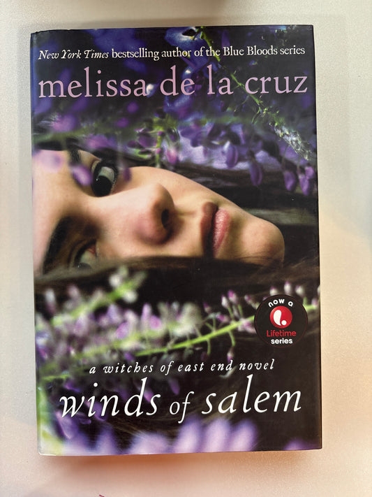 Book cover of 'Winds of Salem' by Melissa de la Cruz with a blurred face and purple flowers.