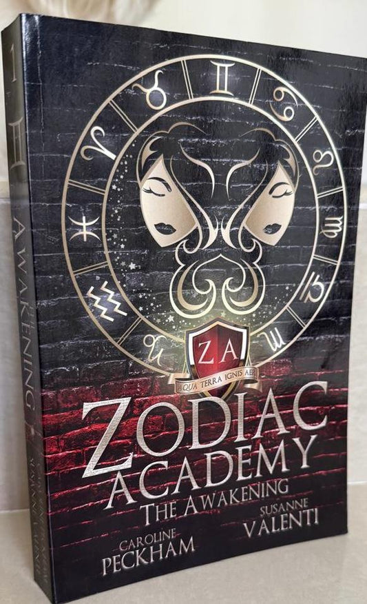 Book titled 'Zodiac Academy: The Awakening' with zodiac symbols on the cover.
