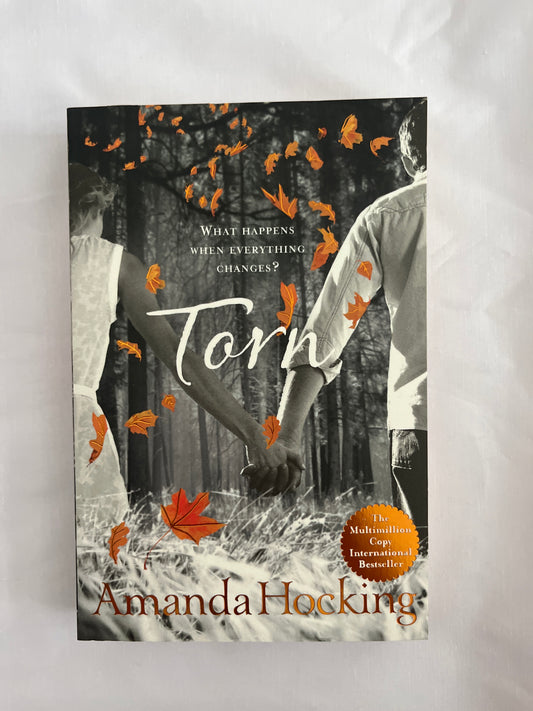 Cover of Torn by Amanda Hocking featuring a blonde girl with windblown hair standing in a mystical, moody landscape with swirling colors and an air of danger
